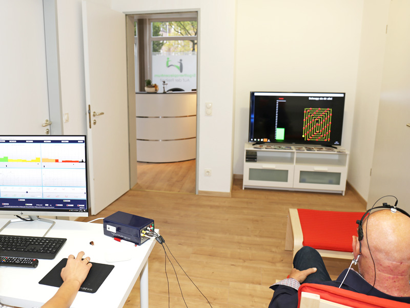 Patient sitzt vor dem Neurofeedback Monitor