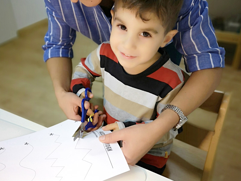 Kind schneidet mit der Therapeutin Papier